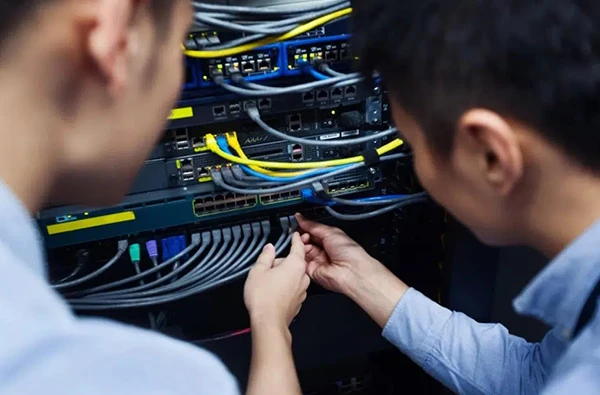Two technicians working on network equipment and wiring to provide fast and reliable internet installation services in Palm Beach Gardens, FL.