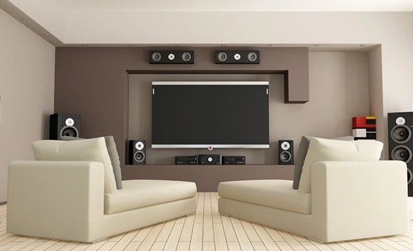 Modern living room with surround sound speakers and large TV, illustrating superior sound system installation services in Palm Beach Gardens, FL.
