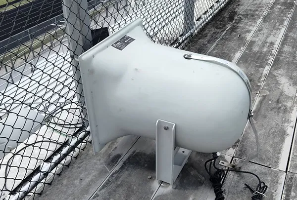 Large white security camera installed on a metal fence, highlighting professional electrical intercom and security system solutions.